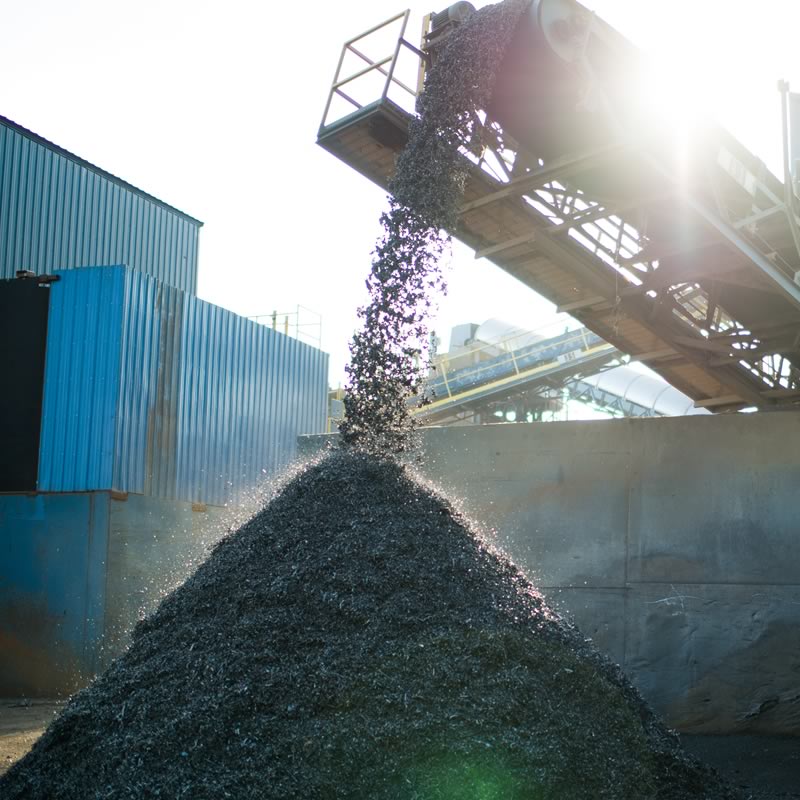 Mound of shredded metals coming off a conveyor belt from shredder.